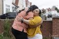 Down syndrome daughter embracing mother in front of house