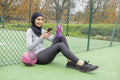 Woman in hijab with basketball ball sitting on basketball court