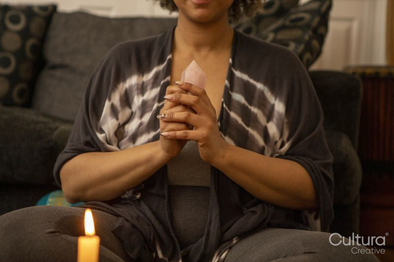 Woman meditating with healing crystal in living room