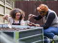 Mother and daughter gardening in backyard