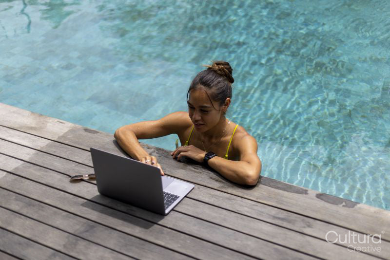 Woman using laptop while relaxing in swimming pool