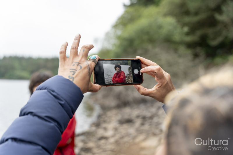 Mother photographing son by lake on hike