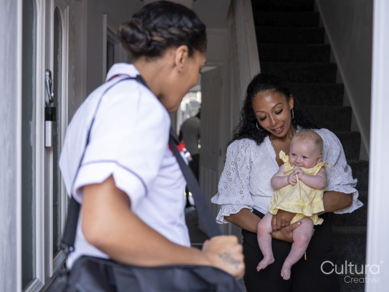 Nurse visiting woman with baby girl at their home