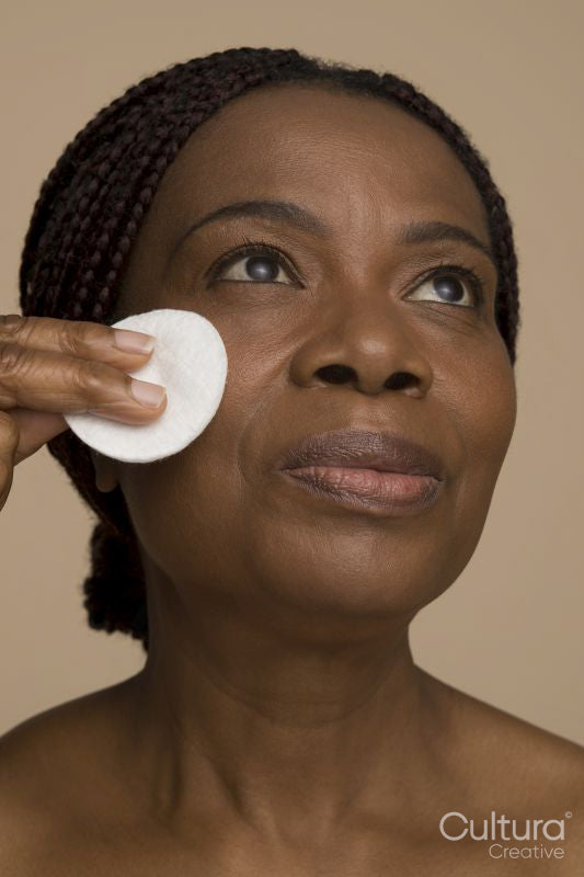 Studio shot of mature woman cleaning face with cotton pad
