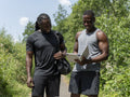 Two men planning workout on digital tablet