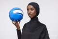 Studio shot of young woman in hijab holding soccer ball