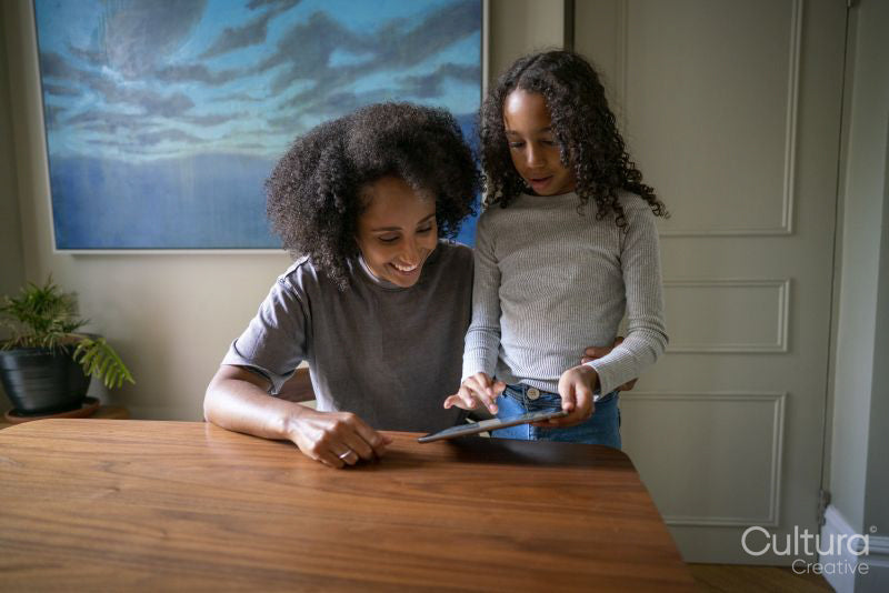 Girl showing digital tablet to mother at home