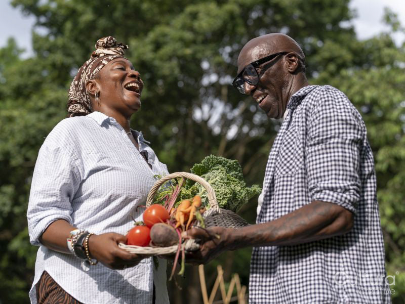 Smiling mature couple holding vegetables from garden