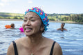 Smiling woman in floral swimming cap in lake, Yorkshire, UK