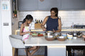 Smiling mother and daughter cooking in kitchen