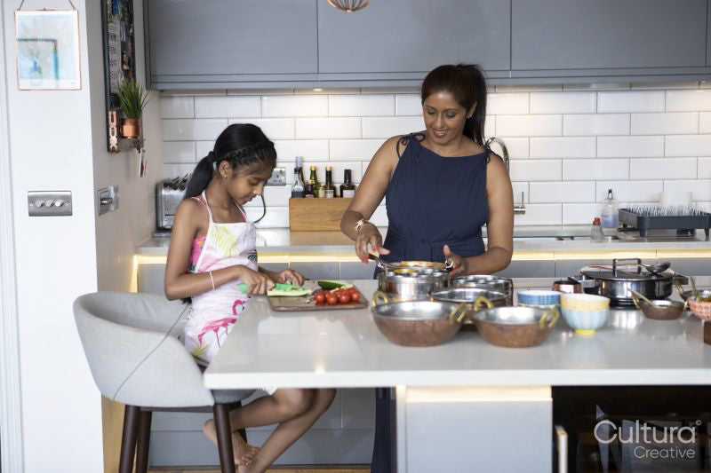 Smiling mother and daughter cooking in kitchen