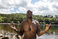 Shirtless man meditating on lakeshore, Yorkshire, UK
