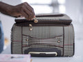 Close-up of person zipping suitcase