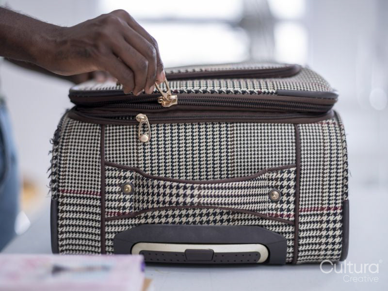 Close-up of person zipping suitcase
