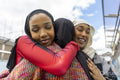 Young women wearing hijabs hugging in city