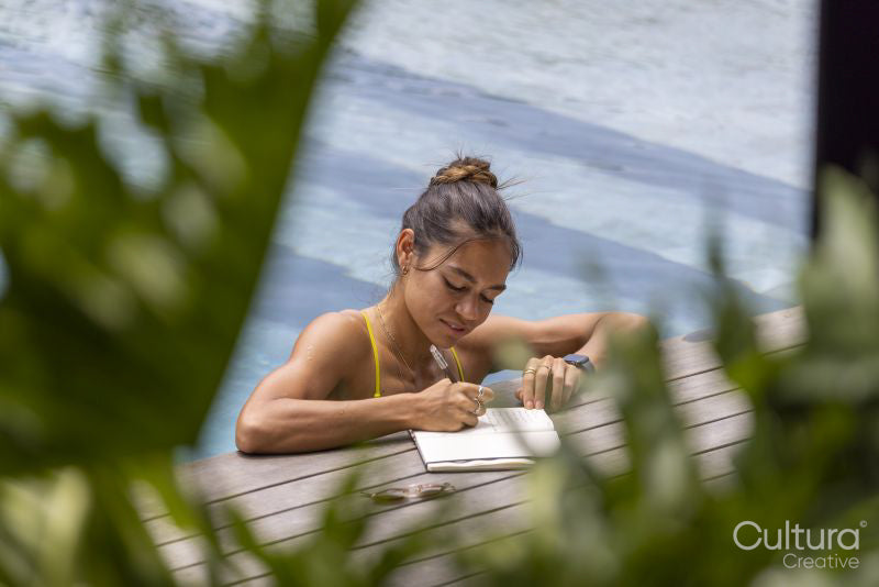 Woman writing in notepad while relaxing in swimming pool