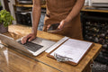 Midsection of cafe owner using laptop and smart phone at counter
