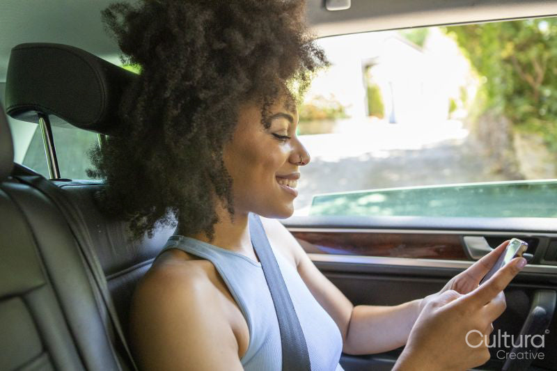 Young woman sitting in car and using smart phone