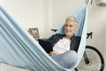 Smiling mature man using digital tablet in hammock