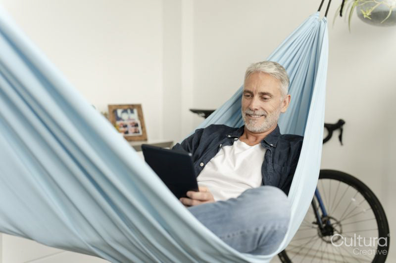 Smiling mature man using digital tablet in hammock