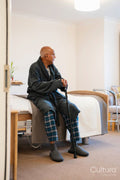 Senior man sitting on bed in room at nursing home