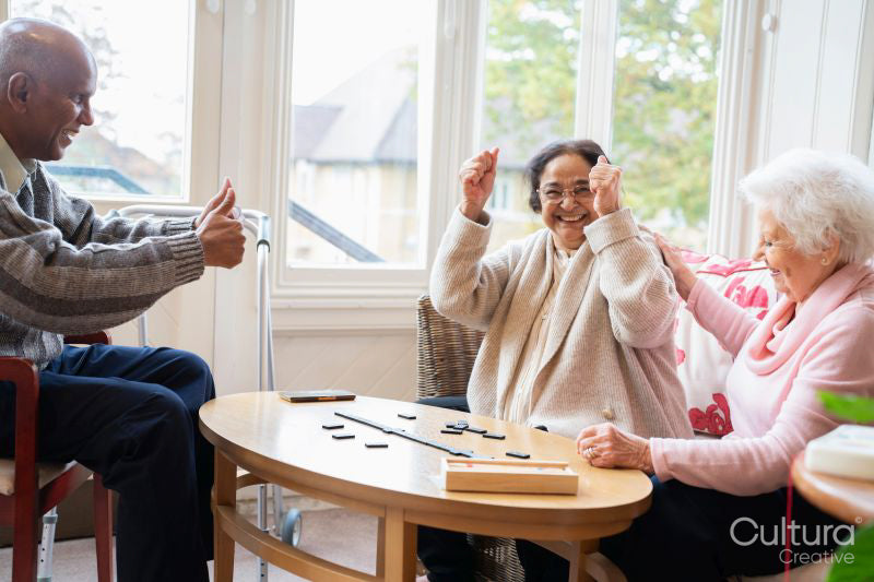 Happy senior people playing domino in nursing home