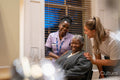 Smiling senior woman with nurse and hairdresser in hair salon