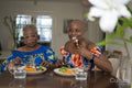 Smiling senior woman with adult daughter eating dinner at table