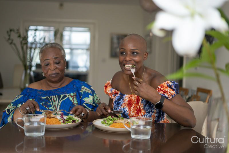 Smiling senior woman with adult daughter eating dinner at table