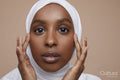 Studio portrait of young woman in white hijab touching face