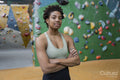 Portrait of woman standing with arms crossed in front of climbing wall