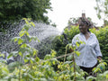 Smiling mature woman watering plants in garden