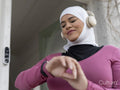 Sutton,Woman in headscarf and headphones checking smart watch