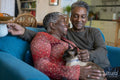 Senior couple with cat sitting on sofa
