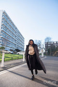 Portrait of smiling woman in long overcoat walking on street