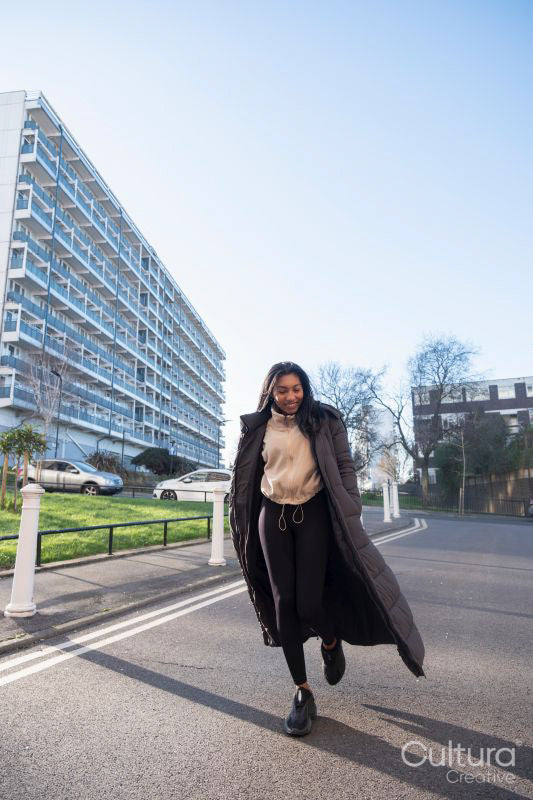 Portrait of smiling woman in long overcoat walking on street
