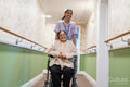 Nurse pushing senior lady sitting in wheelchair at nursing home
