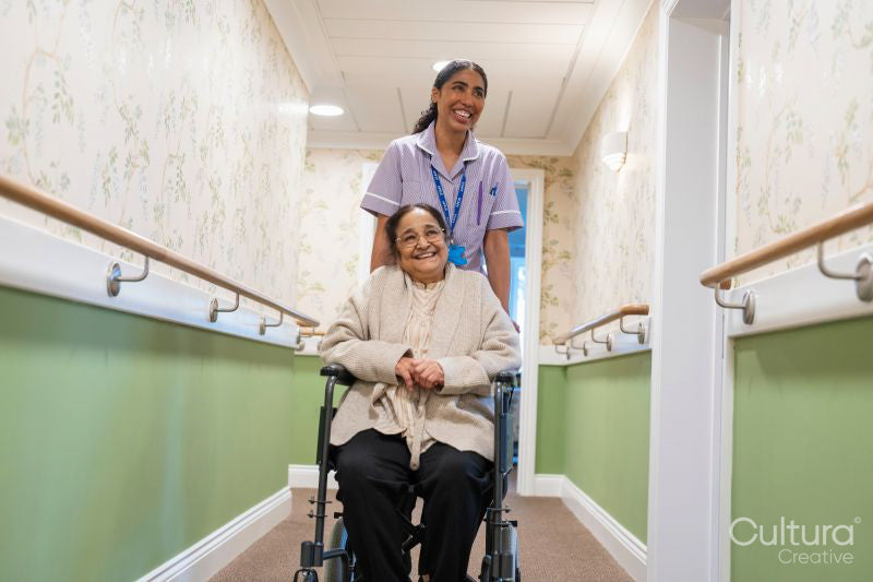 Nurse pushing senior lady sitting in wheelchair at nursing home