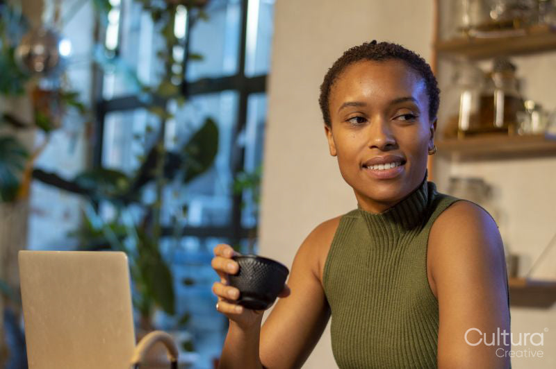 Smiling woman using laptop and drinking tea