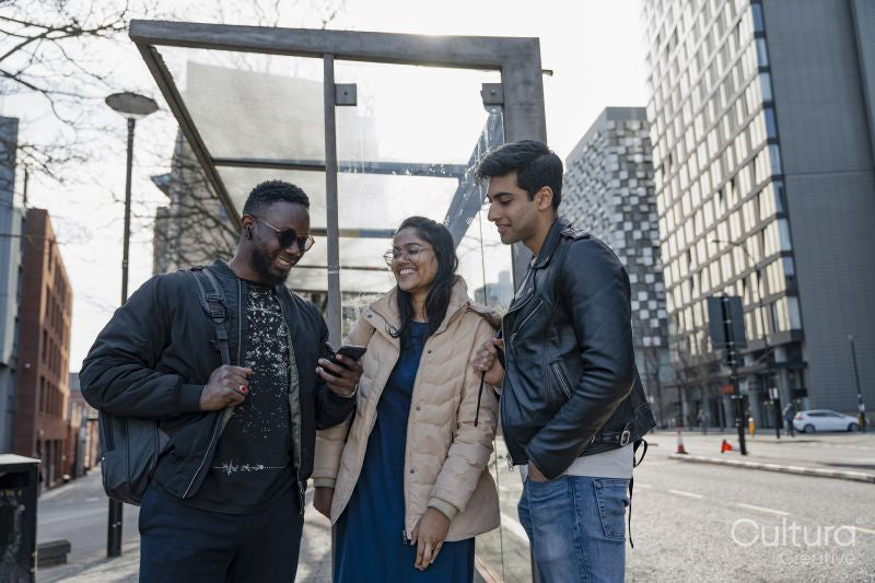 Smiling friends using phone on campus