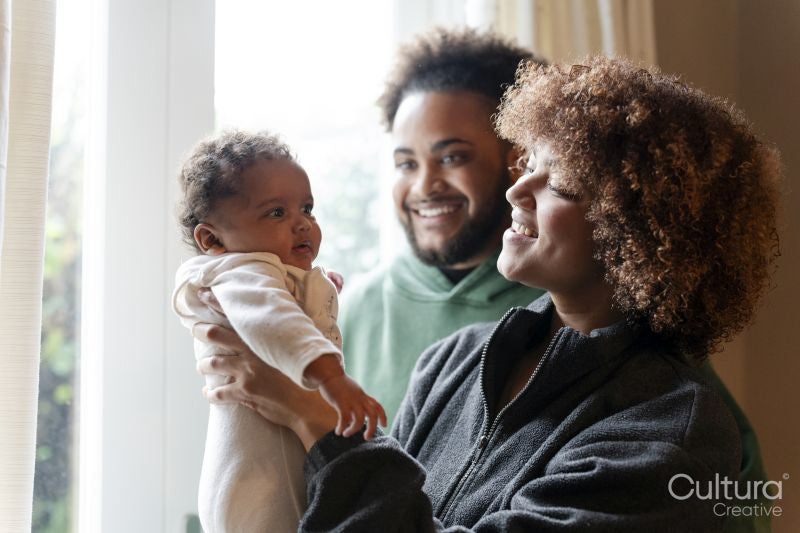 Smiling parents looking at baby daughter at home