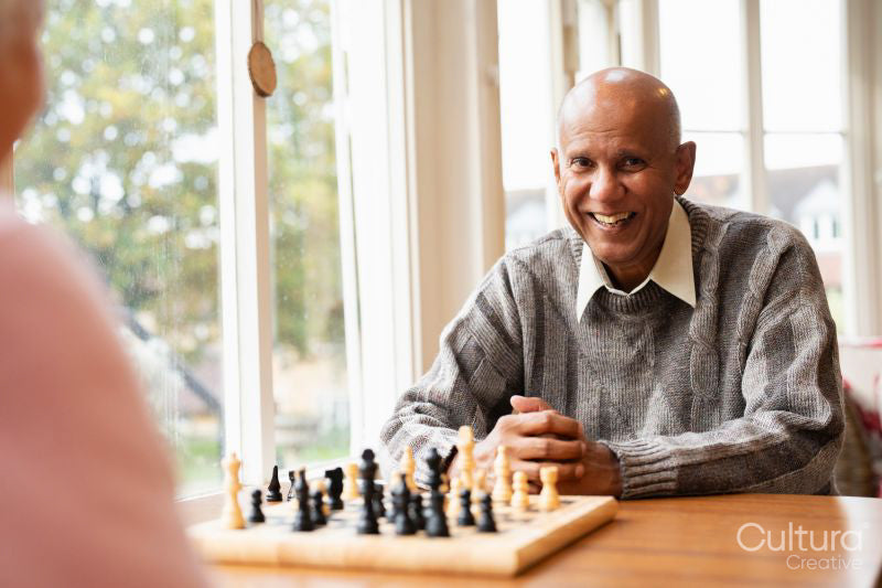 Smiling senior man playing chess in nursing home