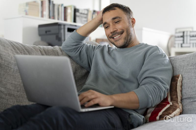 Smiling mature man working on laptop on sofa