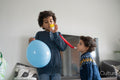 Brothers playing with balloon and party horn blowers
