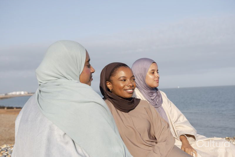 Three Muslim friends sitting on beach