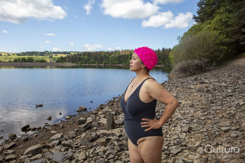 Woman in swimsuit standing on rocky lakeshore, Yorkshire, UK