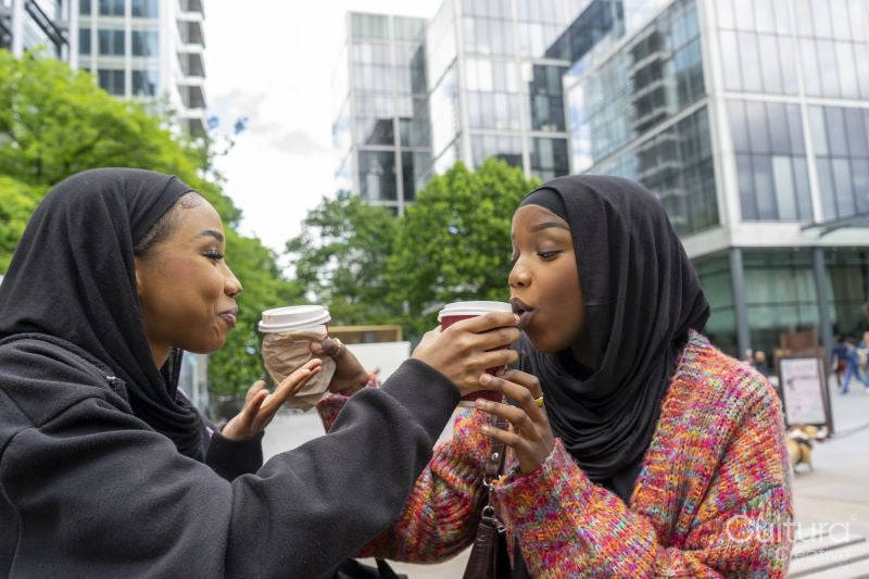 Young women wearing hijabs sharing coffee in city