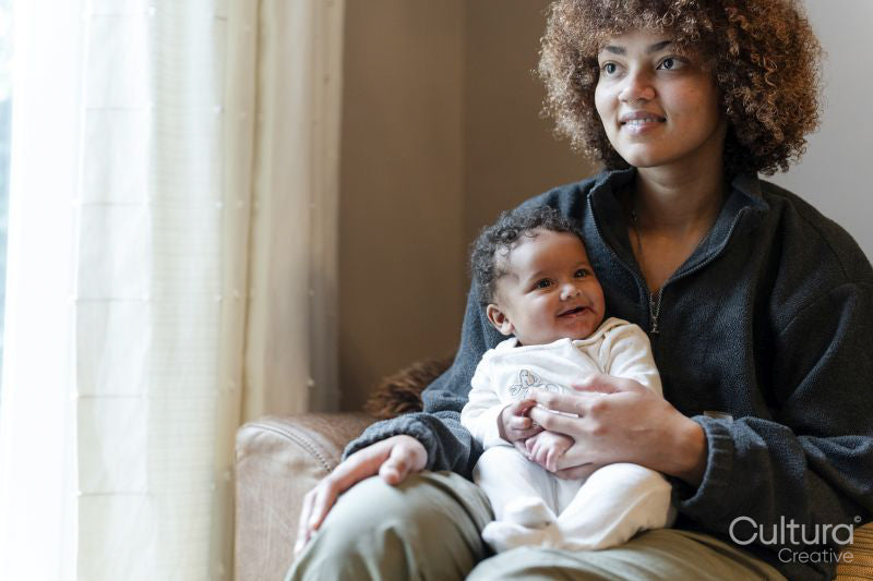 Young mother holding baby girl on lap at home