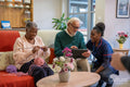 Smiling nurse helping senior man use tablet in nursing home