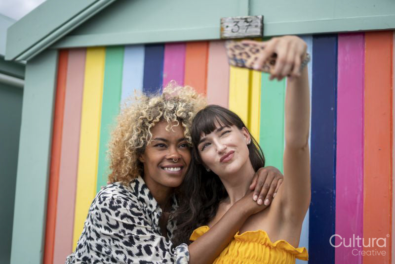 Female couple taking selfie in front of striped wall